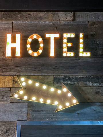 Hotel sign with lights on wooden background