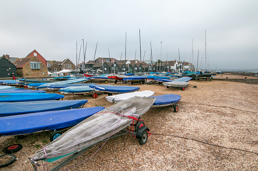 Whitstable Yacht Club at Sea Wall in Kent, England, with shops and people visible in the distance.