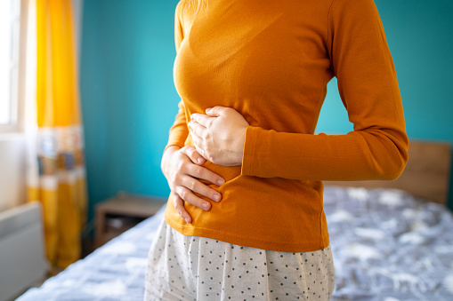 Una mujer irreconocible está sosteniendo su estómago debido a un fuerte dolor photo