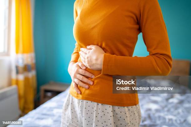 An Unrecognizable Woman Is Holding Her Stomach Due To A Strong Pain Stock Photo - Download Image Now