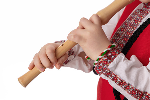 Bulgarian boy musician with flute in traditional folklore costume with martenitsa symbol of spring, Baba Marta and Easter holiday, portrait on white background