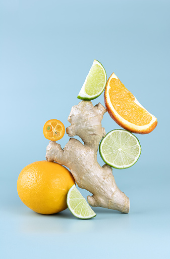Balancing citrus fruits on the table. Citrus pyramid: lime, orange, ginger, lemon and kumquat on blue background. Copy Space