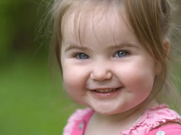 Nice little girl happily smiling and looking at camera