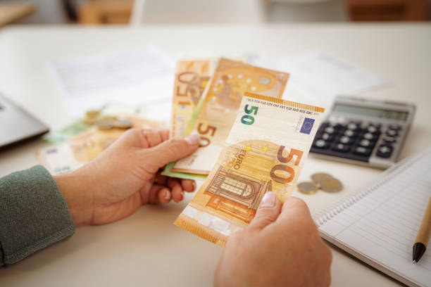 le mani della donna contano le banconote in euro pianificazione del bilancio nazionale - focus on foreground tax close up finance foto e immagini stock