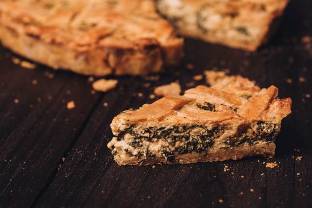 istock Delectable cheese and spinach pie sits on a wooden table, with a portion already cut out 1468597639