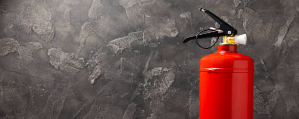istock Fire extinguisher on the background of a black texture wall. Red fire extinguisher indoors on the wall. Fire protection, home fire extinguisher. Mockup, space for text, copy space. 1468598914