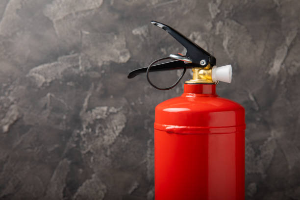 istock Fire extinguisher on the background of a black texture wall. Red fire extinguisher indoors on the wall. Fire protection, home fire extinguisher. Mockup, space for text, copy space. 1468598960