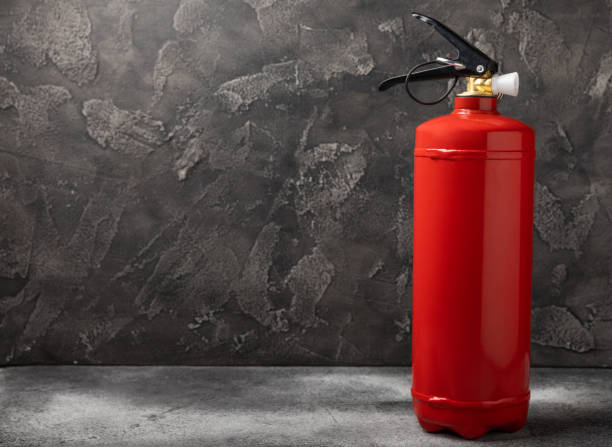 istock Fire extinguisher on the background of a black texture wall. Red fire extinguisher indoors on the wall. Fire protection, home fire extinguisher. Mockup, space for text, copy space. 1468598961