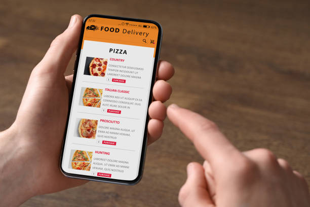 istock Food delivery service. Man choosing dish from menu on site using smartphone at wooden table, closeup 1468600592