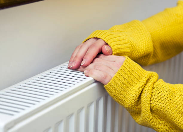 istock The woman warms her hands on the radiator 1468601832