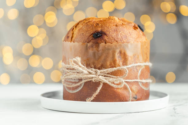 istock Traditional Italian Christmas cake Panettone on the white background. Fruit Easter cake with raisins tied with a jute thread. Festive pastry against blurred bokeh lights background 1468603829
