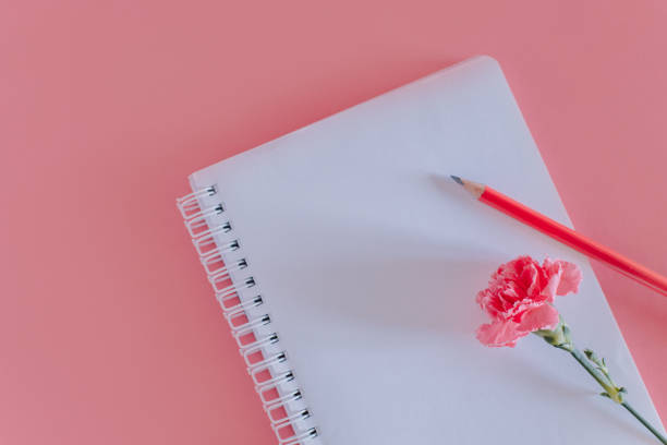 istock Beautiful pink Carnation flower and notebook with pencil on a bright pink background. 1468608671