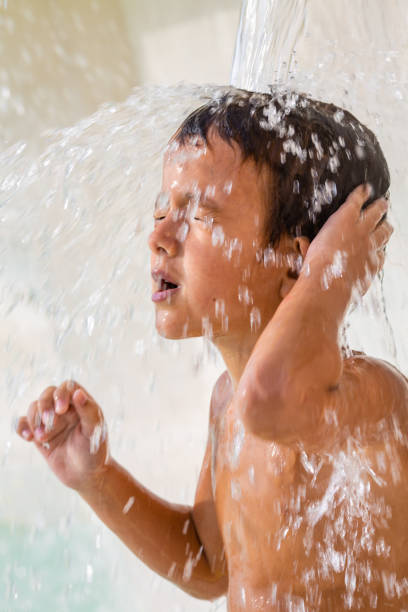 Boy enjoys splashing waterfall and outdoors shower in the summer
