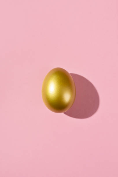 istock Easter template with golden egg. Egg painted gold on pink background. Easter concept with copy space for text. Flat lay style minimalistic design 1468618694