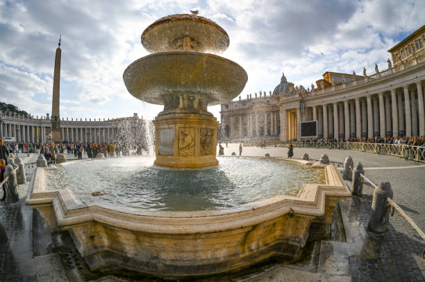 A nighttime view of the illuminated fountain in St. Peter’s Square, Vatican City, with cascading water and colonnades in the background