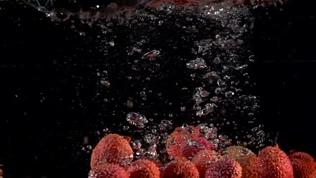 Super slow motion of falling lychee fruit into splashing water. Lemonade cooking concept. Filmed on high speed cinema camera, 4k 1000 fps.