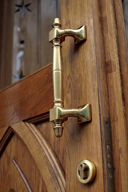 Rubbed brass handle of an old timber door close up