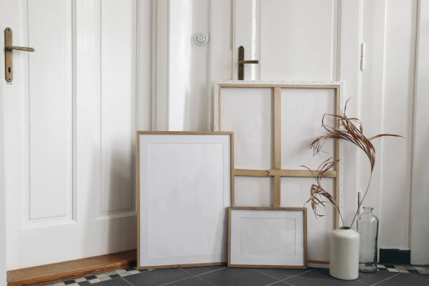 istock Boho wooden picture frames set and blank canvas mockups on grey tiles floor. Artistic still life. Dry palm leaf in vase. Elegant minimal interior design, white wall and old doors background. Home. 1468645963