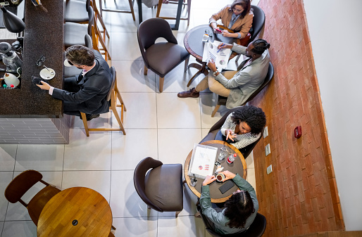 High angle view of multiracial businesspeople sitting at tables in a cafe