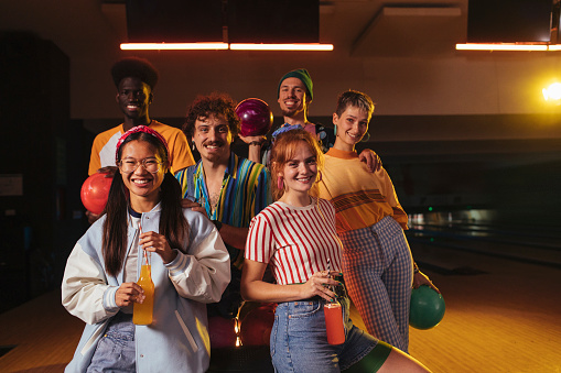 Young multi-racial people standing together for a group photo in a bowling alley