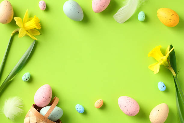 istock Happy Easter greeting card template. Frame made of colorful Easter eggs, daffodil spring flowers on green background. Flat lay, top view, copy space. 1468658502