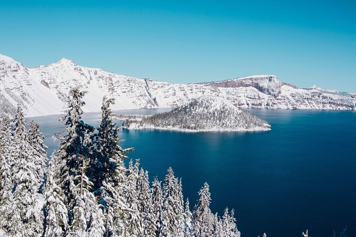 View of Wizard Island in Crater Lake National Park in Oregon during winter. Crater Lake is the only National Park in Oregon and is one of the best travel destinations within the state.