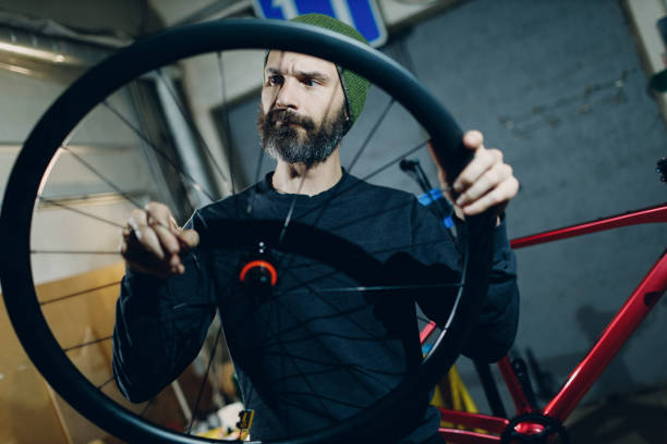 Mechanic repairman assembling wheel custom bicycle in workshop. stock photo