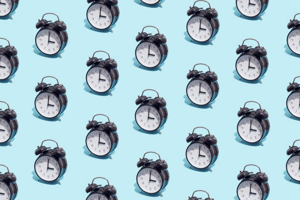 istock Seamless pattern of black retro alarm clocks  show 3 o'clock. Changing clock from summer time to winter time. Shifting the clock hands back in autumn. 1468665534