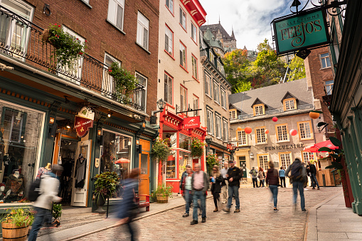 Quebec City, Canada - September 27, 2021: People walk along the old cobblestone sidewalks of Place Royal by the shops and restaurants of historic downtown Quebec city Canada