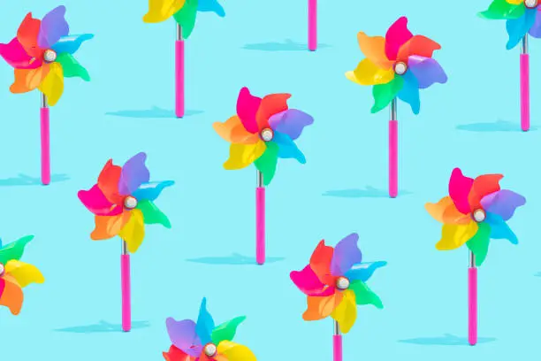 Photo of Isometric seamless pattern made of children`s colorful toy wind turbine isolated on bright blue background.