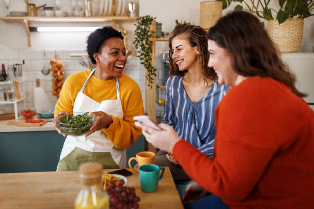 istock Young smiling female friends using phone in the kitchen 1468670756