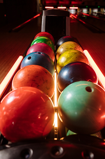 Collection of bowling balls lined up in a bowling alley of various colors