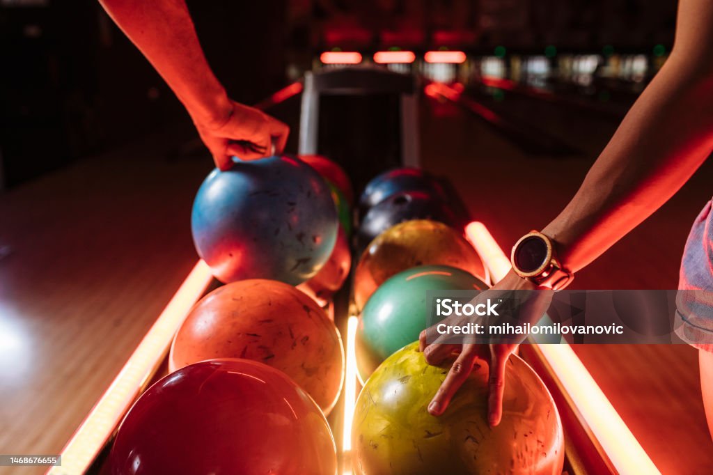 Take one ball Bowling players picking up balls from the rack Ten Pin Bowling Stock Photo