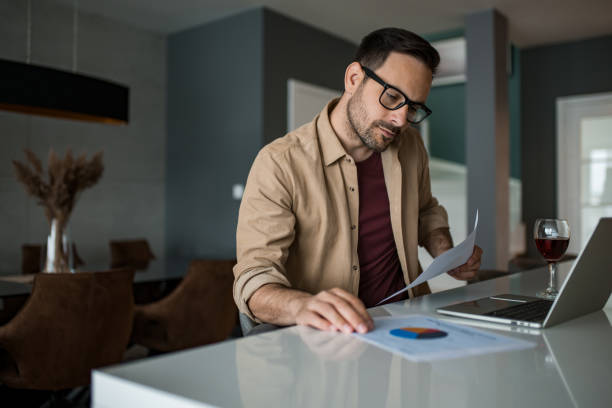 istock Young entrepreneur working at home on laptop and examining business reports. 1468677578