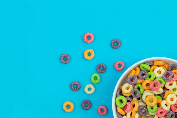 Colored breakfast cereal in a bowl on a blue background, flat lay.