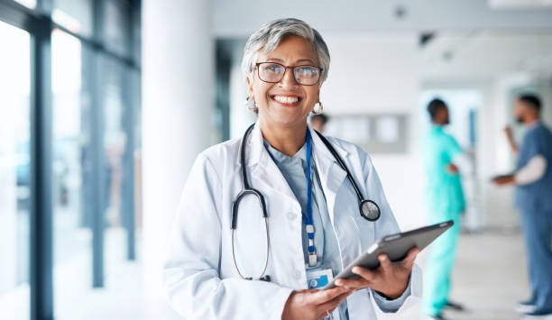 retrato, atención médica y tableta con una mujer médico trabajando en un hospital para investigación o innovación. médico, seguro e internet con una profesional de la medicina femenina parada en una clínica - employee assistance program fotografías e imágenes de stock