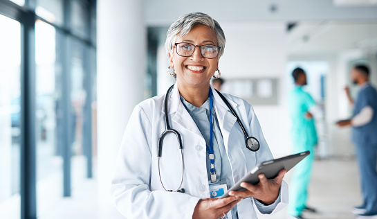Portrait, healthcare and tablet with a doctor woman at work in a hospital for research or innovation. Medical, insurance and internet with a female medicine professional standing in a clinic