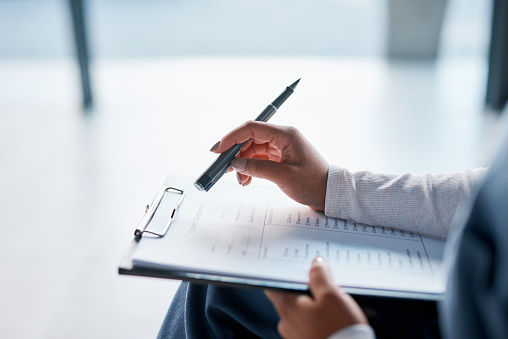 Checklist, clipboard and hands of doctor holding a document or paper taking notes in an office. Closeup, person and healthcare professional with a prescription or insurance paperwork at the workplace