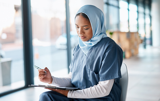 Healthcare, doctor and Muslim woman writing on paperwork for insurance, diagnosis and prescription. Hospital, clinic and Islamic nurse with application form for medical report, review and results