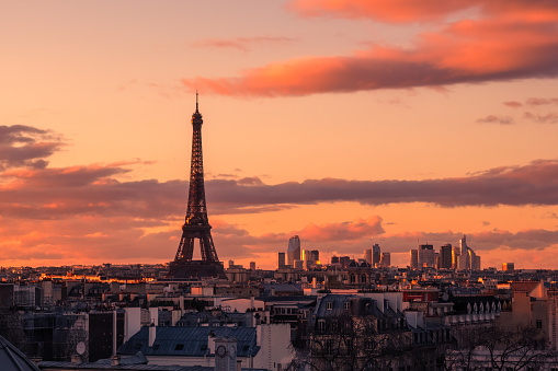 Evening sunshine lighting up the Eiffel Tower and the business district of La Defence viewed over the rooftops of Paris in France