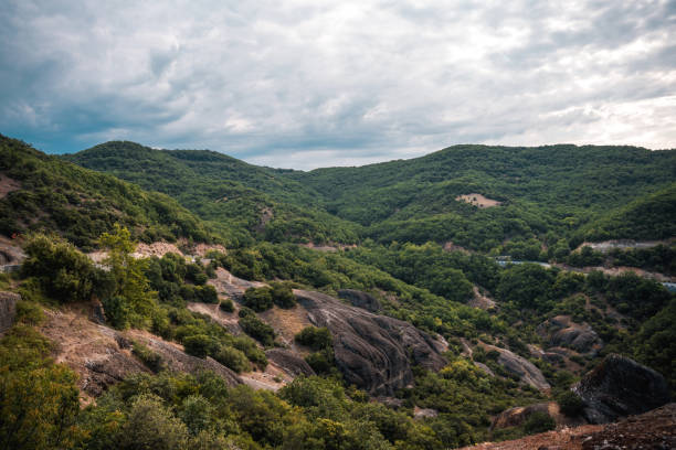 Landscape photo of a valley in Greek Meteora, beautiful background of clouds and sky behind.