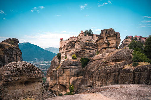 A photo of Unesco World Heritage site with blue sky  in the background and a monastery on top of a hill-shaped boulder.