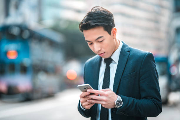 istock Handsome Young Asian Executive Texting With A Smart Phone Outdoors 1468679794
