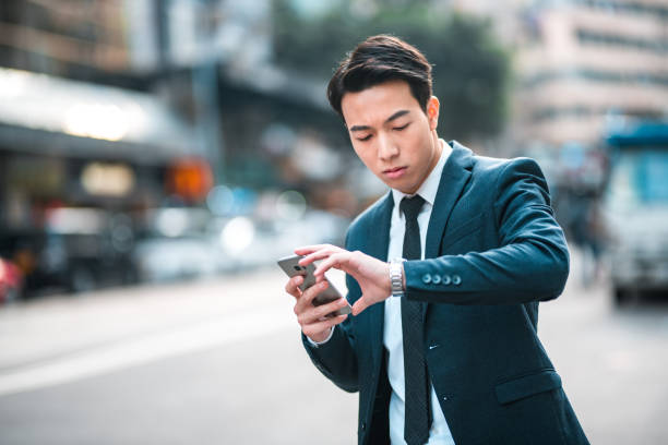 istock Young Asian Businessman Waiting For A Taxi While Using A Smart Phone To Send Emails 1468679801