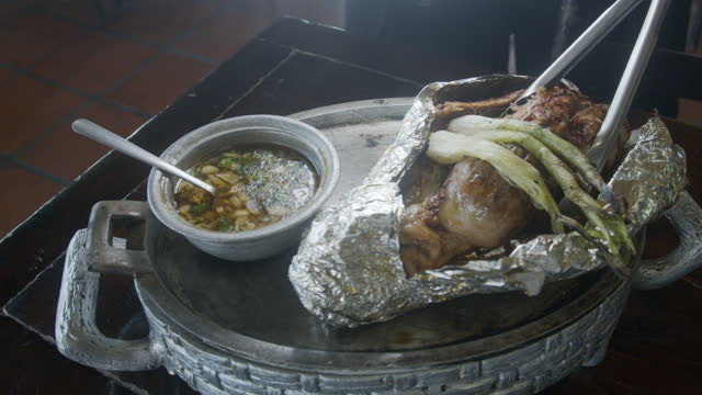 Mexican Style Roasted Chicken on a Pewter Tray with Consommé  Soup and Grilled Green Onion in a Restaurant in Tijuana