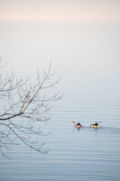Two people kayaking in Lake Erie near sunset on foggy afternoon