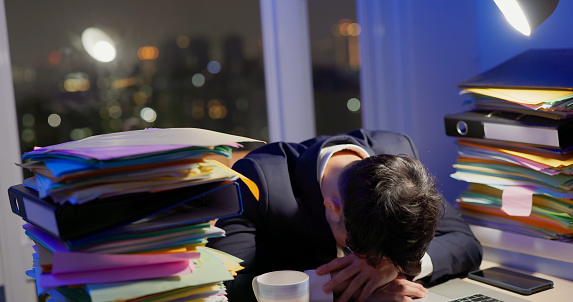asian businessman is overtime work and hardworking at night in office - he feel sleepy