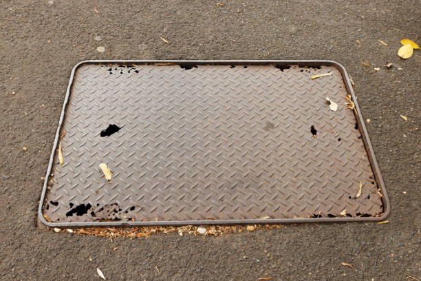 Old rusty metal manhole in a road.