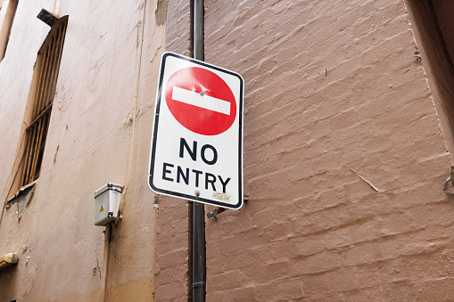 White no entry sign on an old painted brick wall.