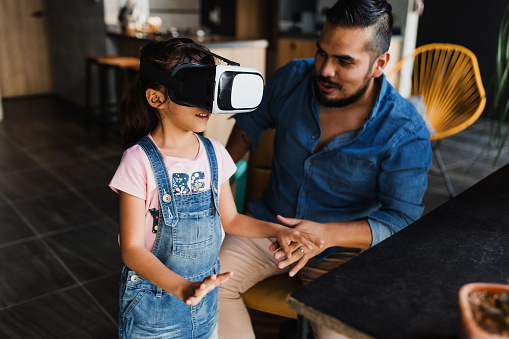 hispanic father playing virtual reality game with his daughter at home in Mexico Latin America